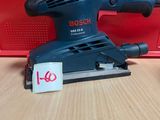 La ponceuse orbitale Bosch est posée sur une table, à côté d'une boîte rouge.
