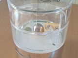 un verre d'eau posé sur une table, avec une cuillère dedans