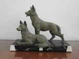statue of two dogs sitting on a marble base on a table
