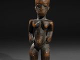 une figurine en bois représentant un homme au corps menu, posée sur une surface noire