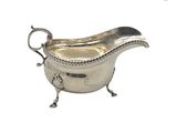 une saucière ancienne en argent, munie de poignées en forme de corde et posée sur un socle