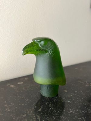 a green bird figurine sitting on a black table
