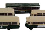 quatre bus miniatures sont alignés en rang sur une surface blanche