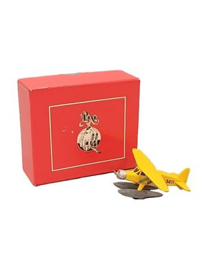 un petit avion miniature à côté d'une boîte rouge contenant des pièces de monnaie