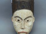 une image représentant un masque en bois au visage blanc et aux cheveux bruns