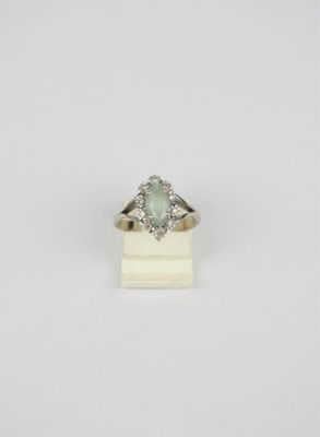 une bague en or blanc sertie d'une pierre verte entourée de diamants