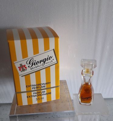 un petit flacon de parfum à côté d'un coffret de parfum