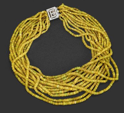 a yellow beaded necklace with a silver clasp on a black background
