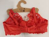 red lace bralette with a wooden hanger on a white surface