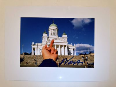 a picture of a person holding a finger up in front of a building