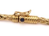 a close up of a gold bracelet with a blue stone on it