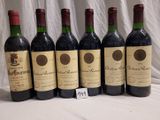 six bottles of red wine are lined up on a table