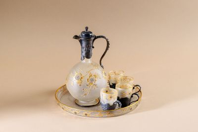 a white and gold pitcher and a cup on a plate