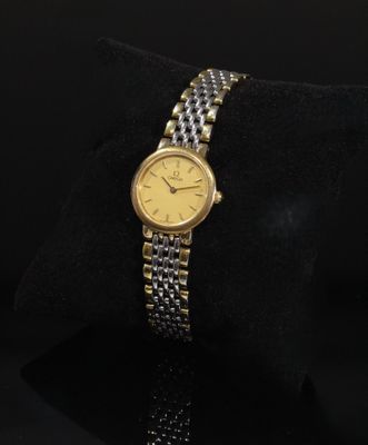 une montre en or et en argent posée sur un coussin noir, sur fond noir