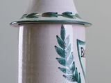 a white and green jar with a green leaf on it