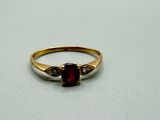 a close up of a gold ring with a red stone on it