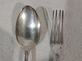 une cuillère et une fourchette en argent posées sur une nappe blanche