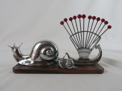 une sculpture en argent représentant un escargot et un éventail, posée sur un socle en bois