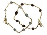 un gros plan sur un bracelet à chaîne en or orné de pierres bleues et vertes