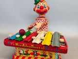 un clown en jouet assis sur une boîte à musique, tenant un instrument de musique