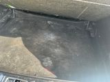 le coffre d'une voiture dont le siège est rabattu et le plancher recouvert de saleté
