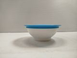a white bowl with a blue lid sitting on a table
