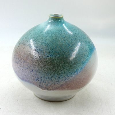 un vase bleu et violet posé sur une surface blanche