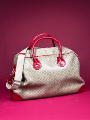 a white and red handbag sitting on top of a pink surface
