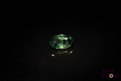 gros plan d'une pierre précieuse verte sur une surface noire