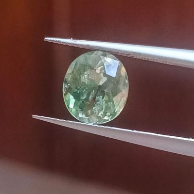 un gros plan d'une pierre précieuse verte tenue par une paire de pinces