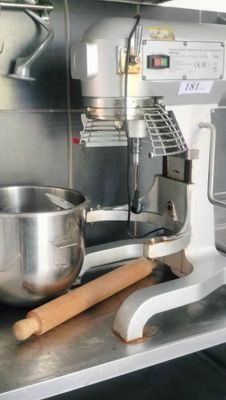 stainless steel counter top with a mixer and a wooden spatula on it