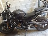 une moto noire garée dans un garage, près d'un mur de briques