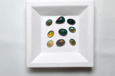 Plusieurs pierres de différentes couleurs sont disposées sur une assiette blanche carrée.