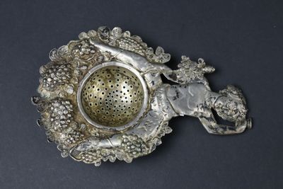 a silver tea strainer with a horse and a bird on it