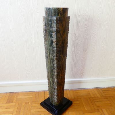 a tall wooden sculpture on a wooden floor in a room
