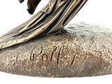 a bronze statue of a woman sitting on top of a rock