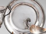 un plateau en argent sur lequel sont posés une tasse et une soucoupe en argent, le tout sur un socle