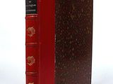 an old red book sitting on top of a white surface