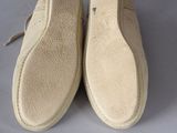 pair of beige slippers on a white surface with a white background