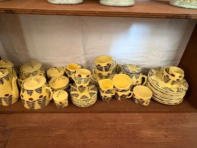 une étagère sur laquelle sont disposées de nombreuses pièces de poterie de styles variés