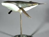 statue of a humpback whale on a stand on a white background