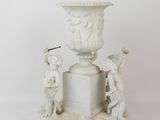 a white vase with statues on top of it