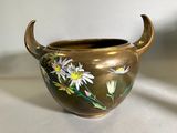 un vase en or orné de fleurs peintes, posé sur une table