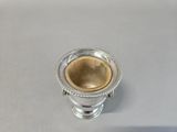 a silver cup with a gold rim sitting on a table