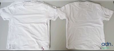 two white t - shirts sitting on top of a table next to each other