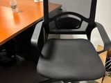 a black office chair sitting in front of a wooden desk