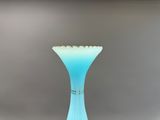 un vase en verre avec un socle bleu posé sur une table