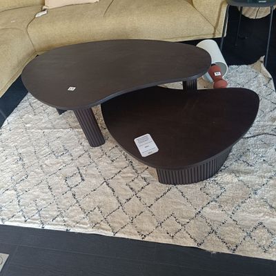 deux tables basses posées sur un tapis devant un canapé