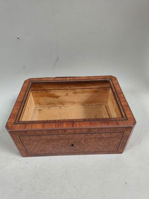 une image représentant une boîte en bois avec un couvercle, posée sur une surface blanche