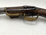 un gros plan d'un pistolet posé sur une surface blanche, avec une crosse en bois